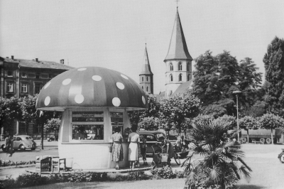 Auf dem Stiftsplatz steht ein Kiosk in Form eines Fliegenpilzes. Im Stamm ist der Verkaufsstand und es sind groß die Worte 