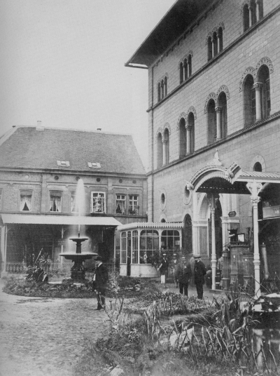 Der östliche Eingang der Fruchthalle ist gut an der Fassade zu erkennen. Ein Springbrunnen und Blumenbeet wirken sehr einladend.