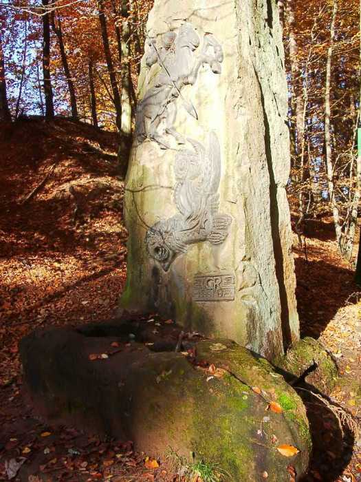 Das Wasser des Brunnens ist verborgen in dem leicht vermosten Stein. Darüber wurde ein weiterer Stein gestellt auf dem ein Ritter ein Ungeheuer bekämpft. © Stadt Kaiserslautern