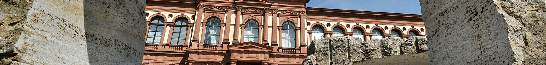 Blick durch eine rechteckige Steinskulptur auf die Außenfassade der Pfalzgalerie