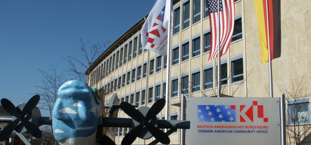 Das rathaus Nord mit dem internationalen Fliegerfisch, dem Deutsch-Amerikanischen Bürgerbüro Schild und gehissten Flaggen deutscher und amerikanischer Nationalität.