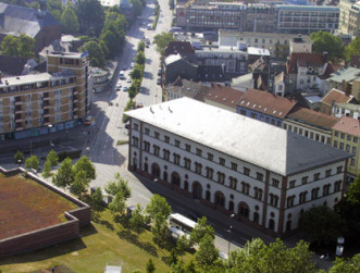 Die Seitenansicht der Fruchthalle von schräg oben, die umgeben wird von grünen Parkanlagen.