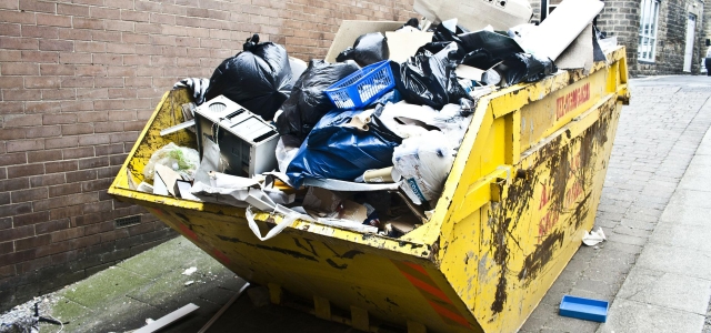 Zu sehen ist ein gelber, mit Müll befüllter Bau-Container.