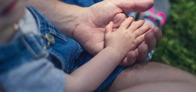 Kind von oben auf Schoß, Hand in Hand mit einem Erwachsenen.