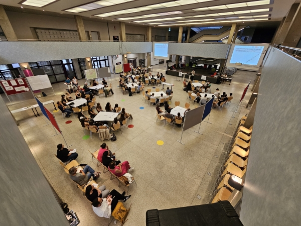 Menschen an Tischen in der Aula